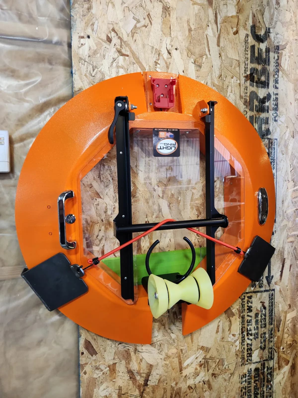 Light Ring stored on a wooden workshop wall with its cover closed.