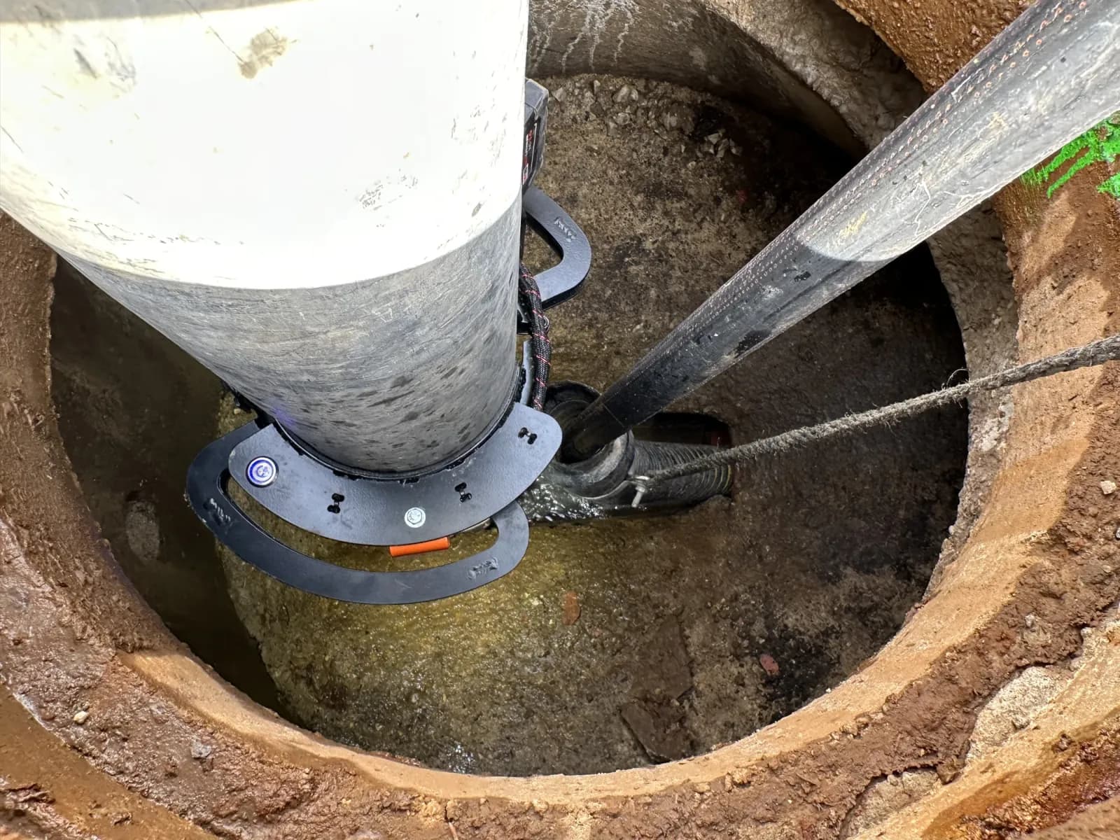 Torch surrounding a vacuum tube inside the rim of a manhole.
