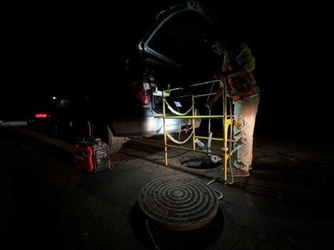 Manhole lighting system illuminating an open manhole during nighttime utility work