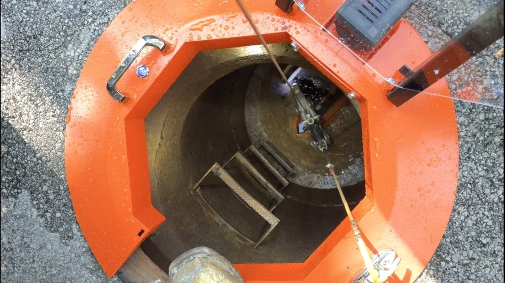 Top-down view of Light Ring manhole lighting system deployed over an open manhole access point showing integrated aluminum safety barrier and interior visibility.