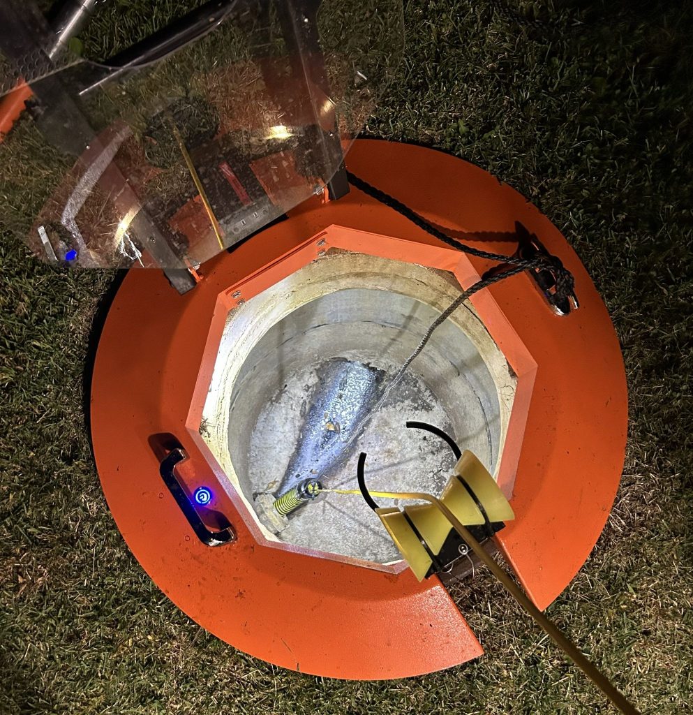 Light Ring manhole fall protection system deployed over open manhole at night with LED illumination active.
